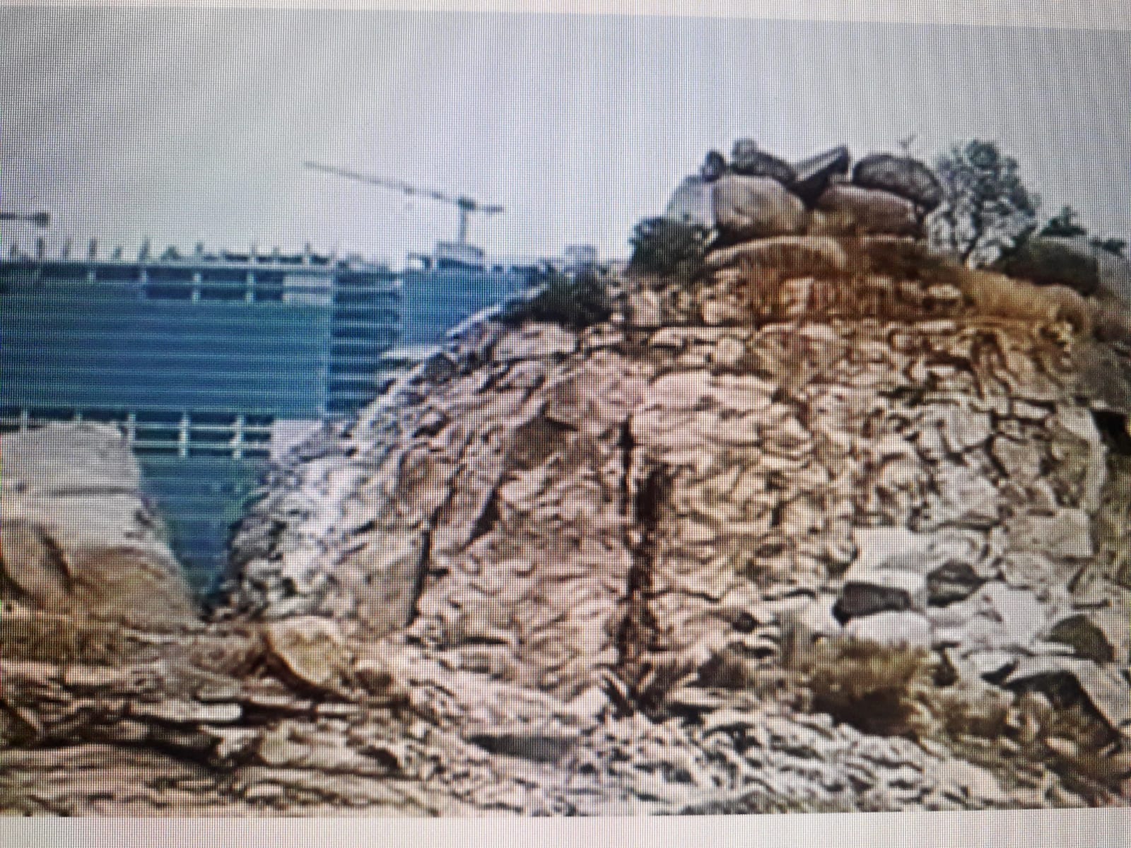 పై ఫొటో గత ఏడాది తీసింది. దీనిలో కుడివైపు కనిపిస్తున్న గుట్ట  విశాలంగా పైకి ఎక్కేందుకు అనువుగా ఉండేది. ఒకప్పుడు ఇది ఆది మానవుల ఆవాసం. దీనిపైన వారు గీసిన చిత్రాలు ఉండేవి. లేఅవుట్ కోసం హెచ్.ఎం.డి.ఎ, ఆ తర్వాత భవనాల నిర్మాణం కోసం బిల్డర్లు ఇక్కడి రాళ్ల గుట్టలన్నీ కొట్టి వేశారు. చారిత్రక సంపద ఉందని తెలిసినా కాసుల కోసం  ప్రభుత్వం ఉదాసీన వైఖరి అవలంభించింది